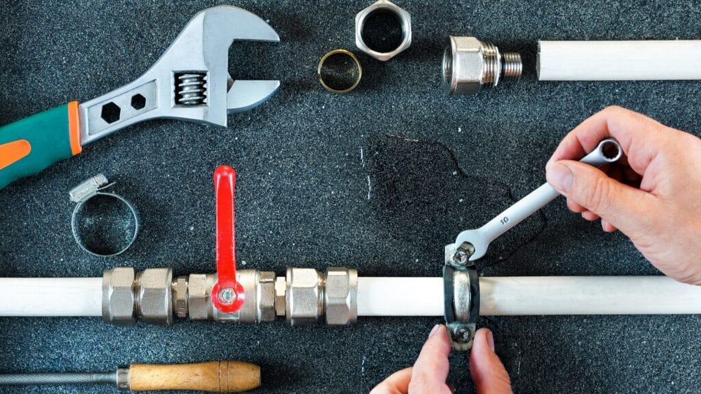 Plumber repairing a pipe valve with an adjustable wrench in New Smyrna Beach