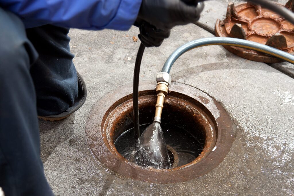 Plumber hydro jetting a sewer line through a manhole in New Smyrna Beach