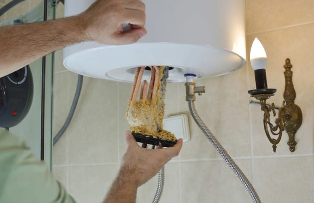 Technician removing mineral buildup from a water heater in New Smyrna Beach